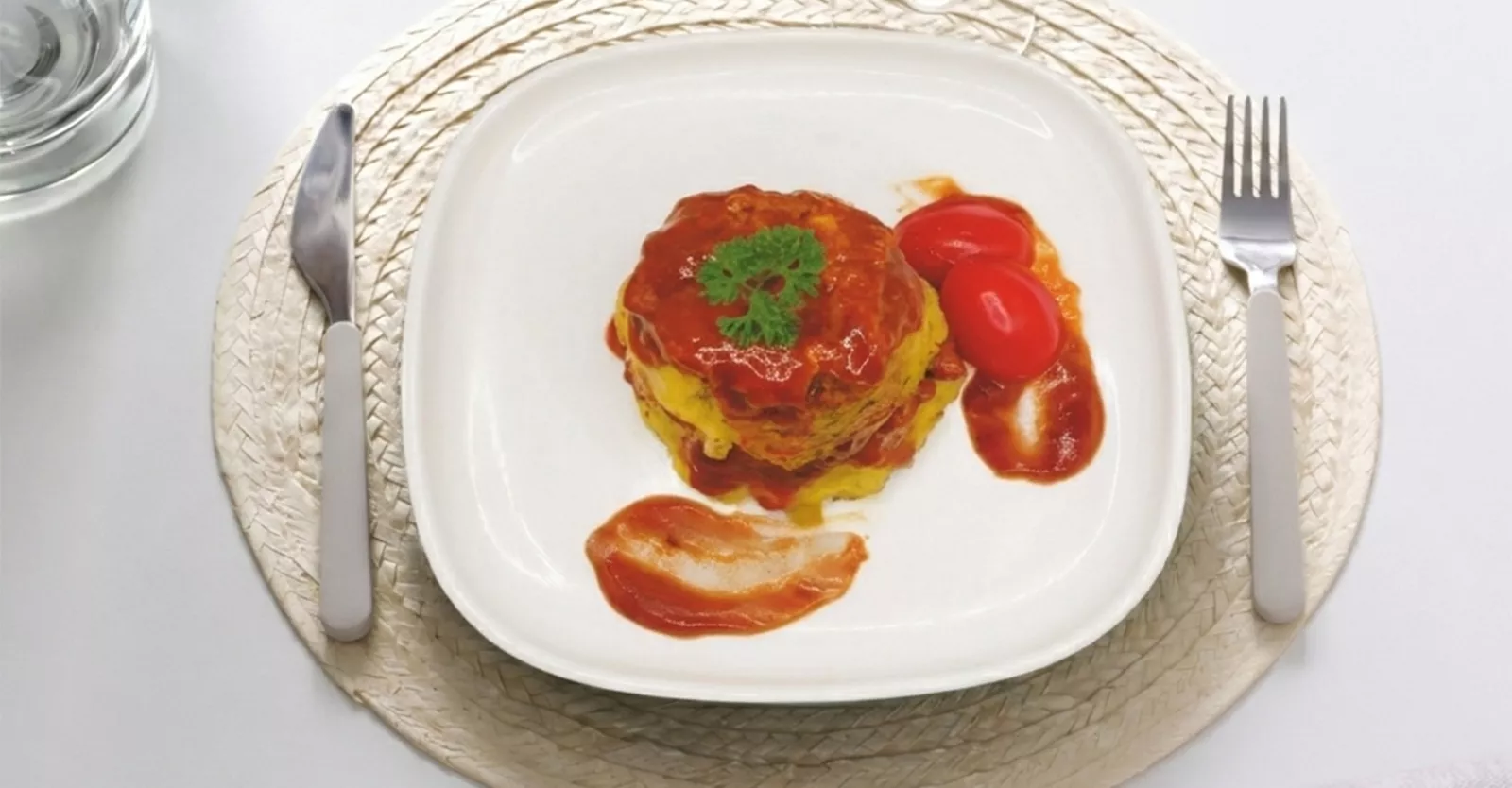 Savory layered dish topped with tomato sauce and cherry tomatoes.