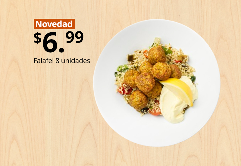 Plato blanco con ocho unidades de falafel sobre cuscús, salsa y rodaja de limón.