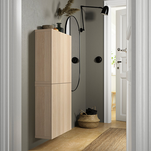 Wood BESTÅ unit with black handles, wall lamp, wicker basket, rug.