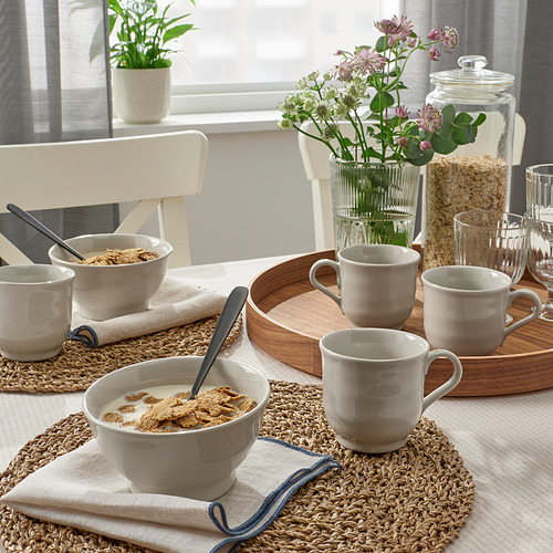 Un acogedor comedor con tazones de cereales, tazas y flores en una bandeja de madera rústica.