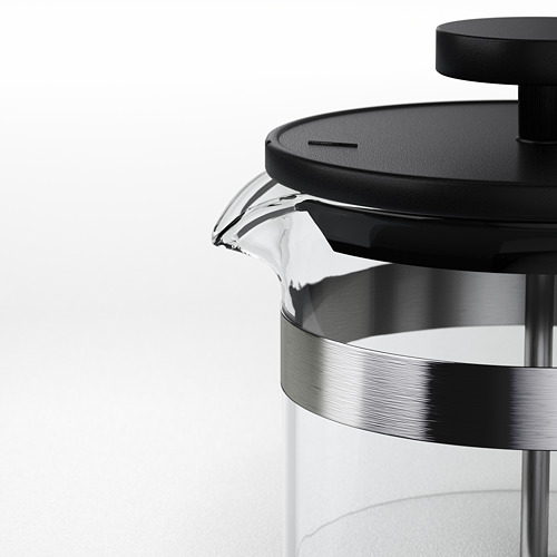Cafetera de vidrio transparente con tapa de plástico negro y base de acero inoxidable.
