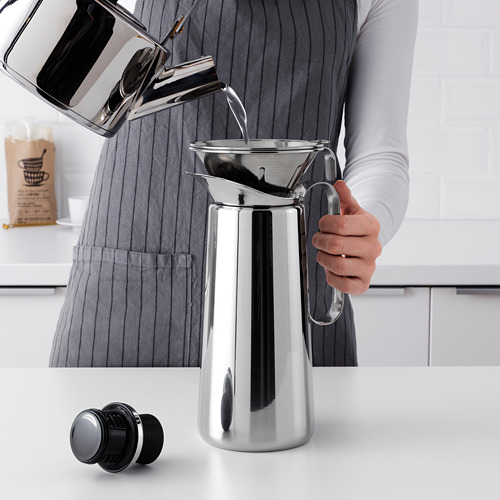 Verter agua en una cafetera elegante y moderna con filtro reutilizable en la encimera.