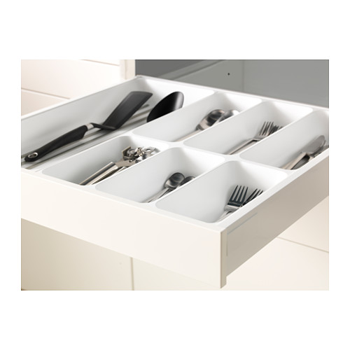 White kitchen drawer organizer with compartments holding spoons, forks, knives, and cooking utensils. Part of the METOD kitchen system.