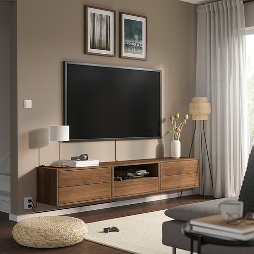 Sala de estar moderna con TV montada en la pared en la unidad EKET. Cajones, estantes y accesorios de madera. Cortinas ligeras, alfombras y cojines.