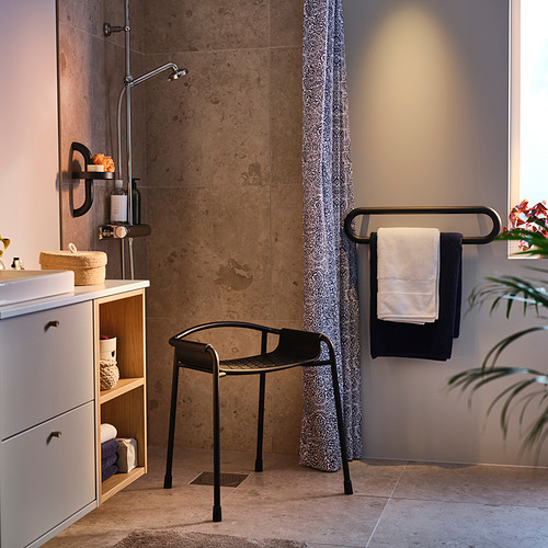 Baño moderno con estante de ducha gris oscuro BÄSINGEN, toallero colgante, mueble lavabo blanco y cortina de ducha estampada.