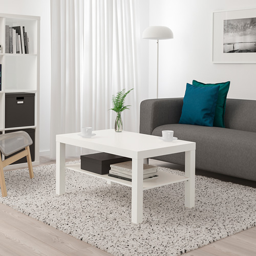Moderno salón con mesa de centro LACK entre sofá y silla. Sostiene tazas, plantas y libros.