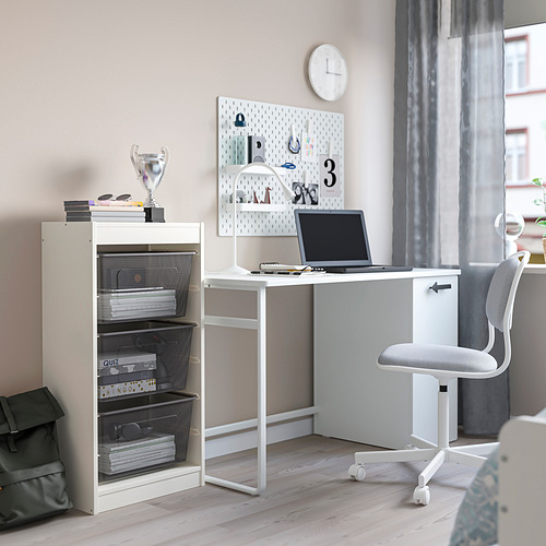 Moderna área de estudio para niños con almacenamiento TROFAST, escritorio, computadora portátil y artículos de papelería. Los cajones de malla contienen libros y trofeos; reloj en la pared.