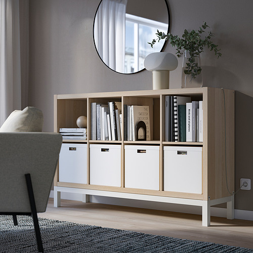 Estantería KALLAX blanca con libros, decoración, plantas y espejo.