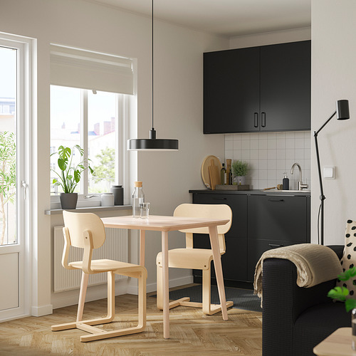 Cocina moderna con mesa de chapa, sillas ligeras, lámpara colgante y plantas.