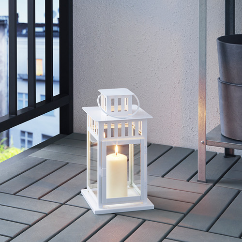 Linterna blanca con vela encendida en la cubierta de madera, que proporciona un suave resplandor y ambiente.