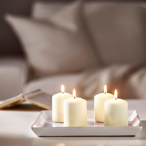 Cuatro velas encendidas en una bandeja, creando un ambiente acogedor.
