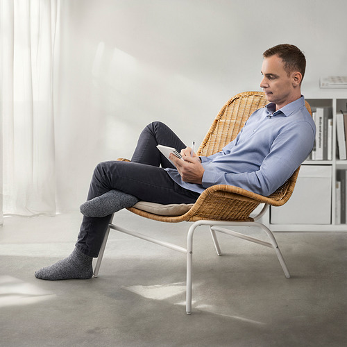 Silla de mimbre natural con hombre sentado, sosteniendo papel. Diseño elegante para mayor comodidad.