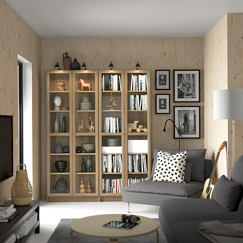 Moderno salón con librerías BILLY, sofá gris, mesa redonda y apliques. Fotos en blanco y negro en la pared.