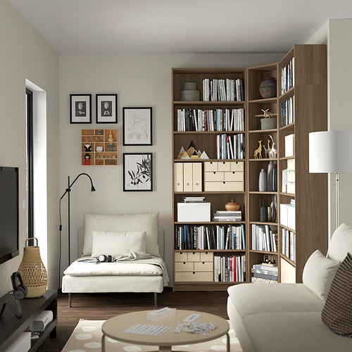Acogedora sala de estar con estantería BILLY, silla, sofá, mesa de café y lámpara. Obras de arte y decoración en las paredes.
