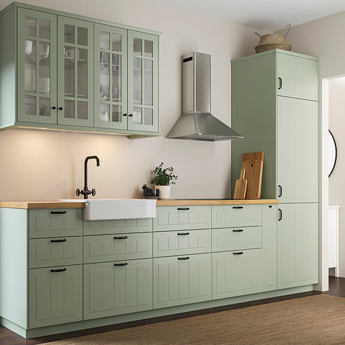 Cocina moderna STENSUND verde: encimera de madera clara, fregadero, campana de acero inoxidable, armario alto con cesta, planta en maceta, tablas de cortar.