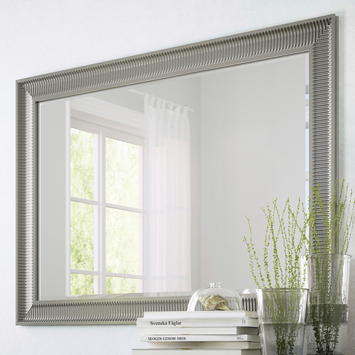 Large mirror with vertical & horizontal hang options, reflective surface, with safety film. Shown on wall reflecting window, next to plants & books.