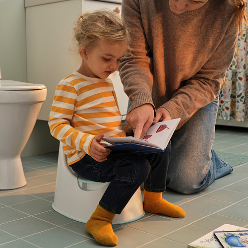 La niña aprende a usar el baño con la ayuda de un adulto.