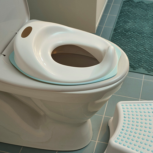 Un asiento de entrenamiento para ir al baño para niños TOSSIG blanco, con bordes suaves, colocado en un inodoro.