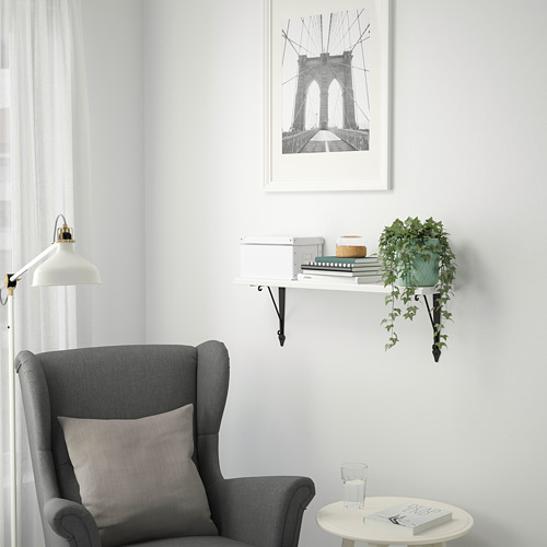 Acogedor rincón con silla, mesa pequeña y estante de pared con decoraciones y plantas.