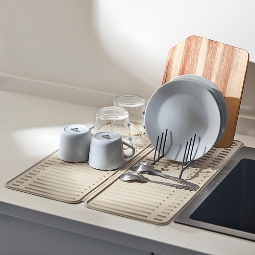 Encimera de cocina con alfombra RINNIG que sostiene platos y utensilios organizados, cerca de la tabla de cortar de madera.