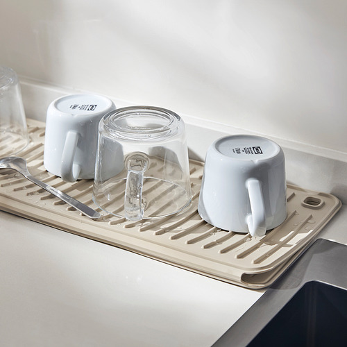 Alfombrilla de secado debajo del escurridor de platos con tazas y vaso.
