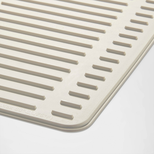 Primer plano de una alfombra de secado beige texturizada con ranuras verticales diseñada para uso en la cocina.