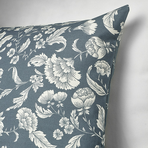 Cojín cuadrado con fondo azul e intrincado diseño floral blanco.
