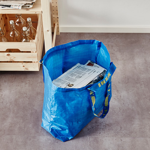 Blue ikea FRAKTA bag on floor, holding papers.