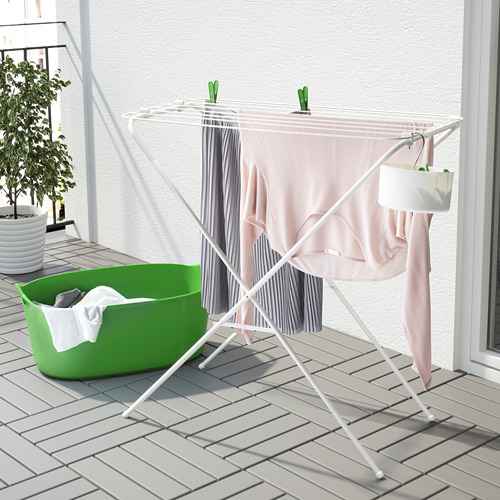 Un tendedero plegable blanco con ropa, con una cesta verde con la ropa, apto para uso en interiores o exteriores.