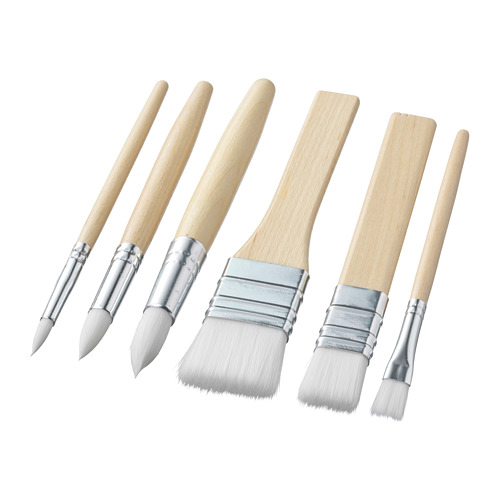 Seis pinceles blancos con mangos de madera, virolas y varias formas de cerdas, dispuestos sobre un fondo blanco.