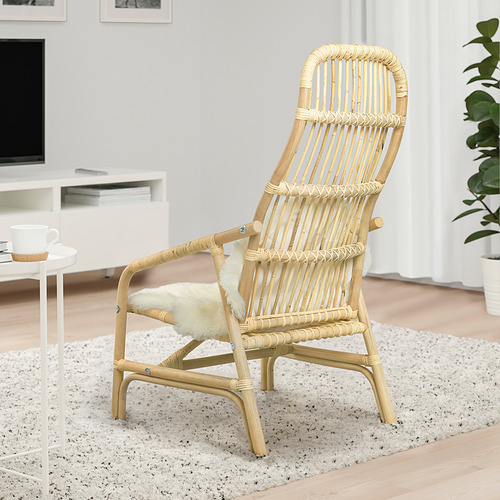 Sillón de ratán natural con cojín de piel crema; Ambiente elegante y relajado con una decoración moderna.