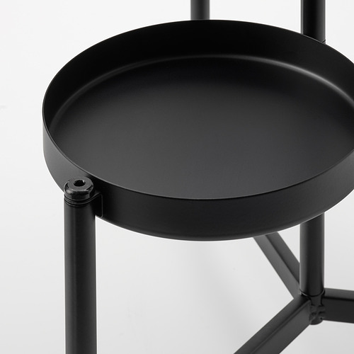 Soporte para plantas de metal negro, con patas robustas e interconectadas y una bandeja circular para exhibir las plantas.