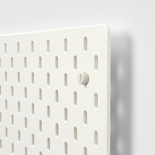 Tablero perforado blanco con orificios espaciados uniformemente, con un botón central blanco, fijado a una pared lisa.