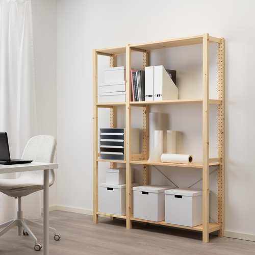 Oficina en casa con estante de almacenamiento de madera clara IVAR, que sostiene cajas blancas, libros y jarrones junto a un escritorio con una silla blanca.