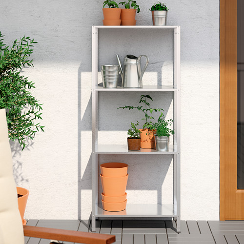HYLLIS: estantería de exterior de metal blanco con tres niveles. Sostiene ollas, cubos. Adyacente a la puerta y plantas en macetas.