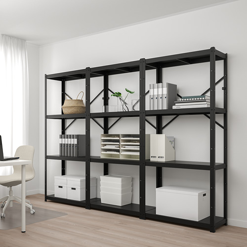 Estantería metálica BROR negra con múltiples cajas de almacenamiento y libros, más grande que el escritorio y la silla de al lado.
