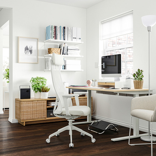 Moderna oficina en casa con escritorio MITTZON con silla blanca, computadora, plantas y libros.