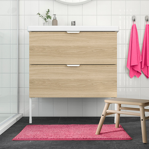 Baño moderno con tocador de madera clara, toallas rosas y alfombra de baño TOFTBO.