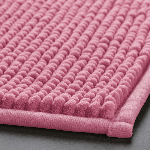 Primer plano de la alfombra de baño rosa suave, que muestra su superficie texturizada y su material de microfibra de felpa.