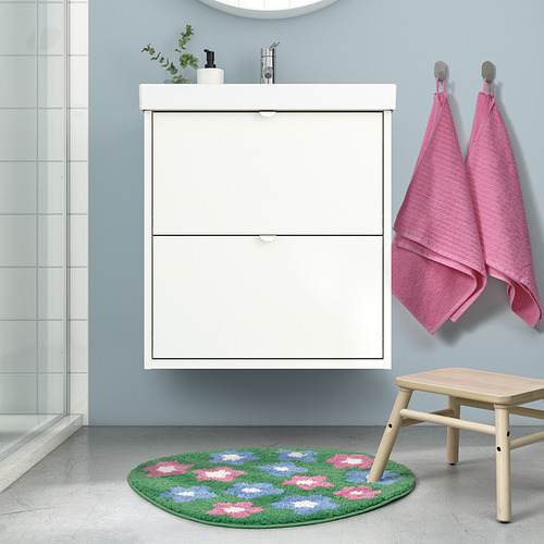 Baño con mueble blanco, lavamanos, espejo. VATTENSKRUV alfombra de baño verde con flores, taburete, toallas rosas.