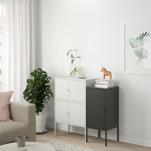 Sala de estar minimalista con gabinete LIXHULT blanco, caballo de madera oscura, planta verde y sofá de color claro.