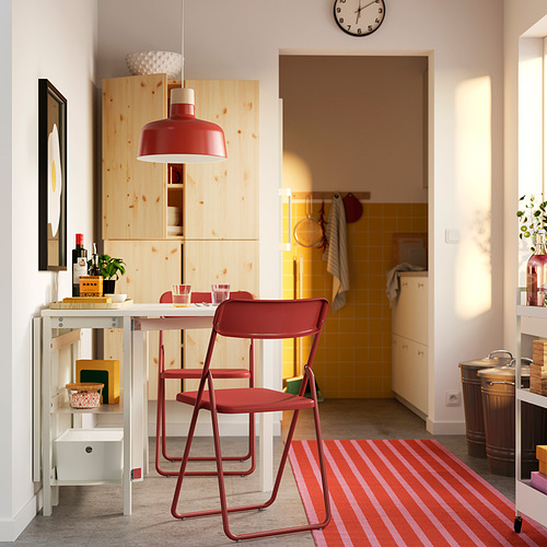 Cocina luminosa con sillas VIHALS rojas, estanterías de madera, alfombra y lámpara colgante.
