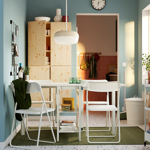 Comedor minimalista con sillas VIHALS plegadas debajo de la mesa, alfombra blanca, de madera, verde.