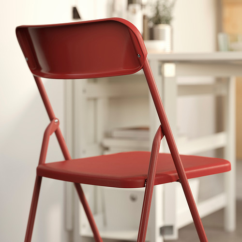 Silla plegable VIHALS de color rojo brillante en la habitación, mostrando su diseño ligero y apilable. Listo para montar, cómodo, duradero para uso en interiores.