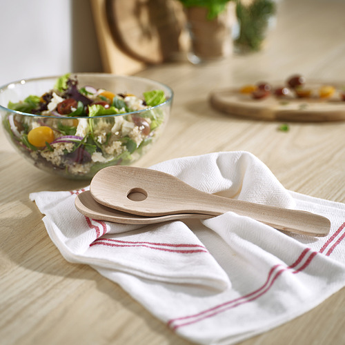 Ensaladeras de madera SKALLKNEKT en marrón claro, descansando sobre una tela a rayas cerca de un tazón de verduras mixtas. Diseño pequeño y redondeado.