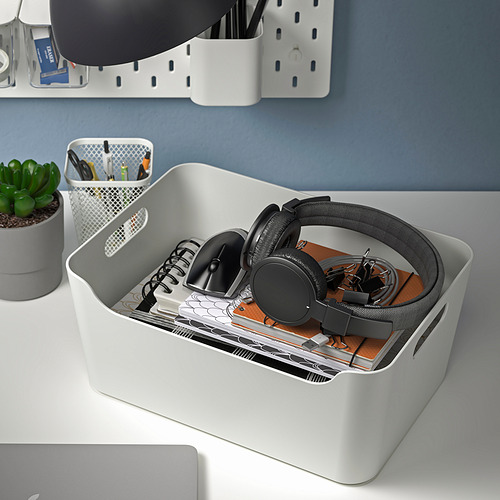 Caja organizadora blanca sobre el escritorio, con capacidad para auriculares, cuadernos y bolígrafos, con asas para facilitar su transporte.