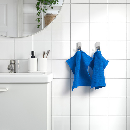 La toalla azul VÅGSJÖN cuelga junto al lavabo. Color brillante, algodón suave. Tamaño mediano, con un estilo impecable.