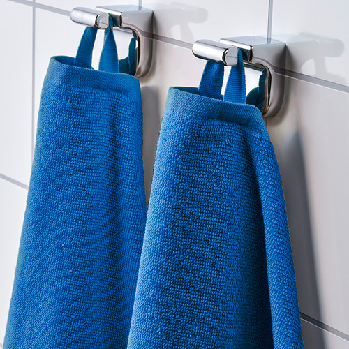 Dos toallas de baño azules cuelgan de ganchos metálicos, mostrando su textura de algodón suave y absorbente y su diseño de secado rápido.