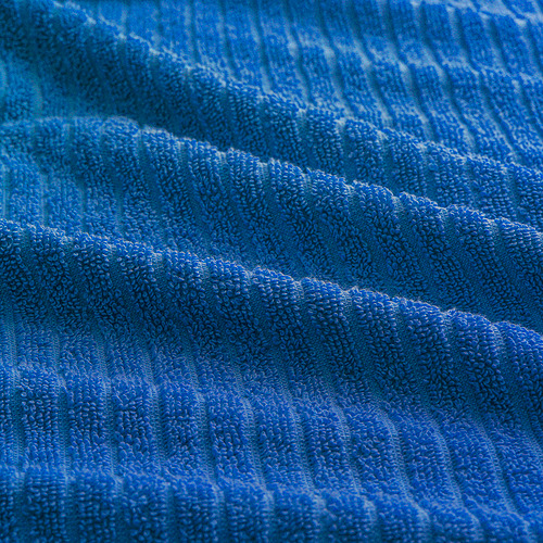 Primer plano de material de felpa azul, texturizado. Tejido acanalado suave, absorbente y visible. La textura similar al cielo azul agrega atractivo visual.