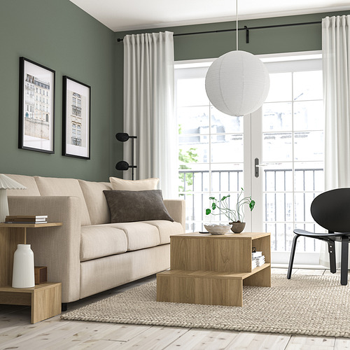Sala de estar moderna con lámpara GULLSUDARE sobre mesa de café, resplandor cálido, grandes ventanales, sofá beige, silla negra.